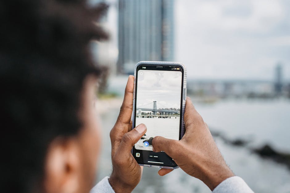 Black man taking photo of bridge over river