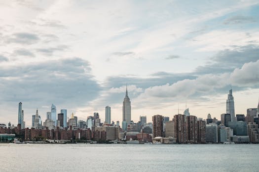 Cityscape of contemporary metropolis with high rise towers located on river shore under cloudy sky