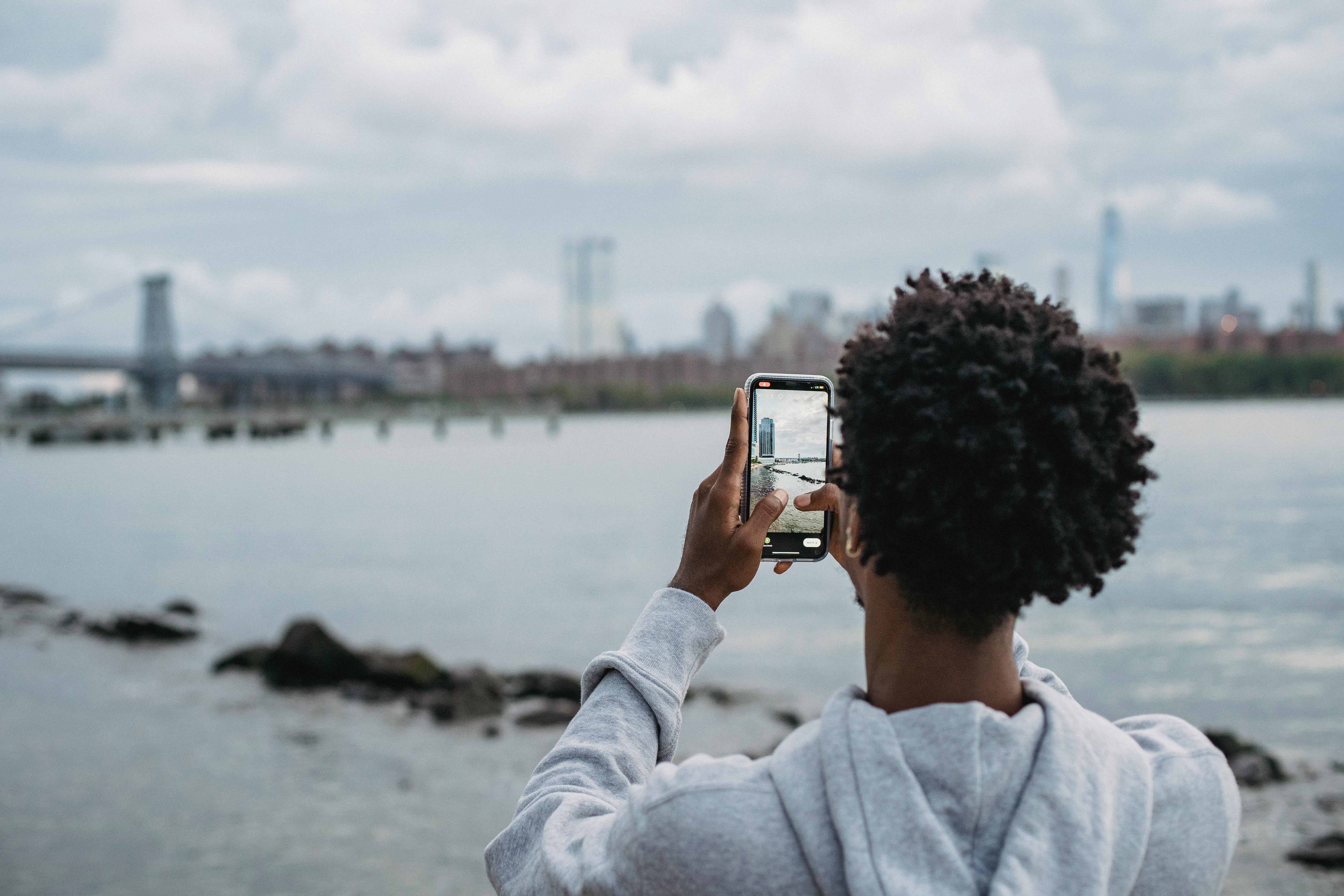 black man taking photo of bridge on smartphone