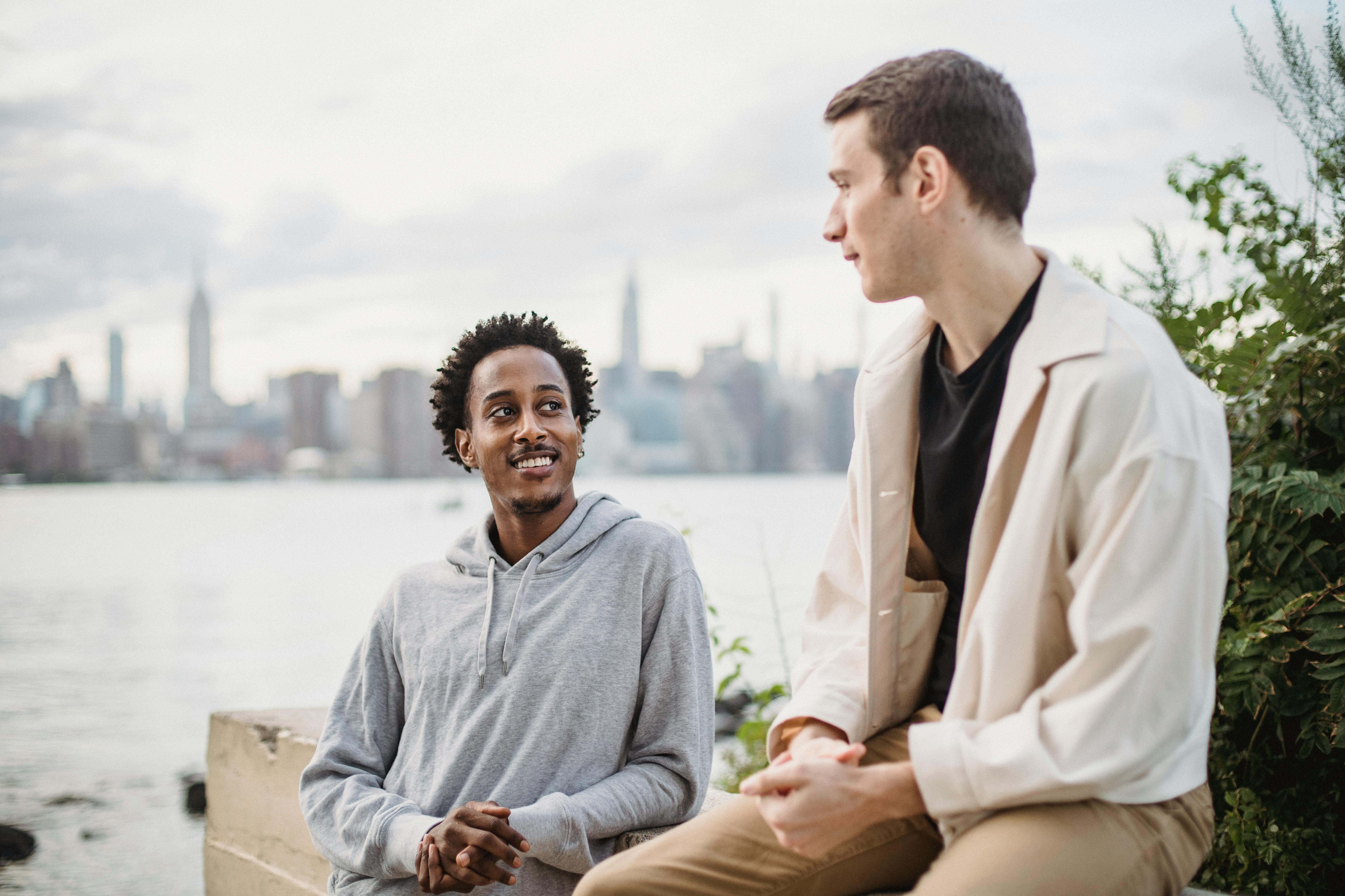 smiling black man talking to friend on river embankment