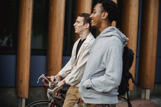Two diverse young men enjoying a casual walk outdoors with a bicycle.