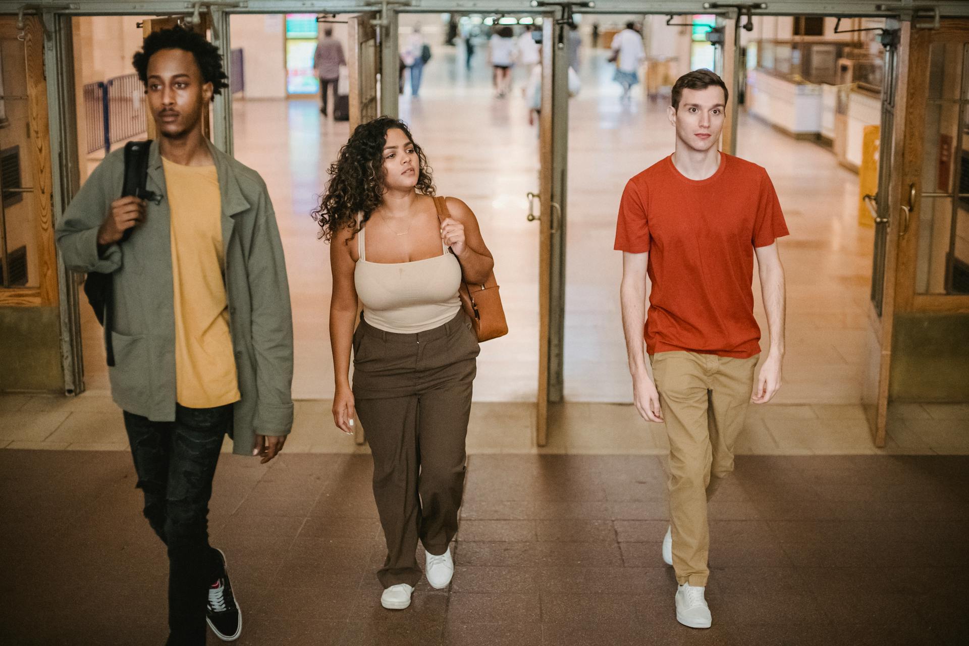 Group of multiethnic people walking together through opened doors in spacious shopping mall