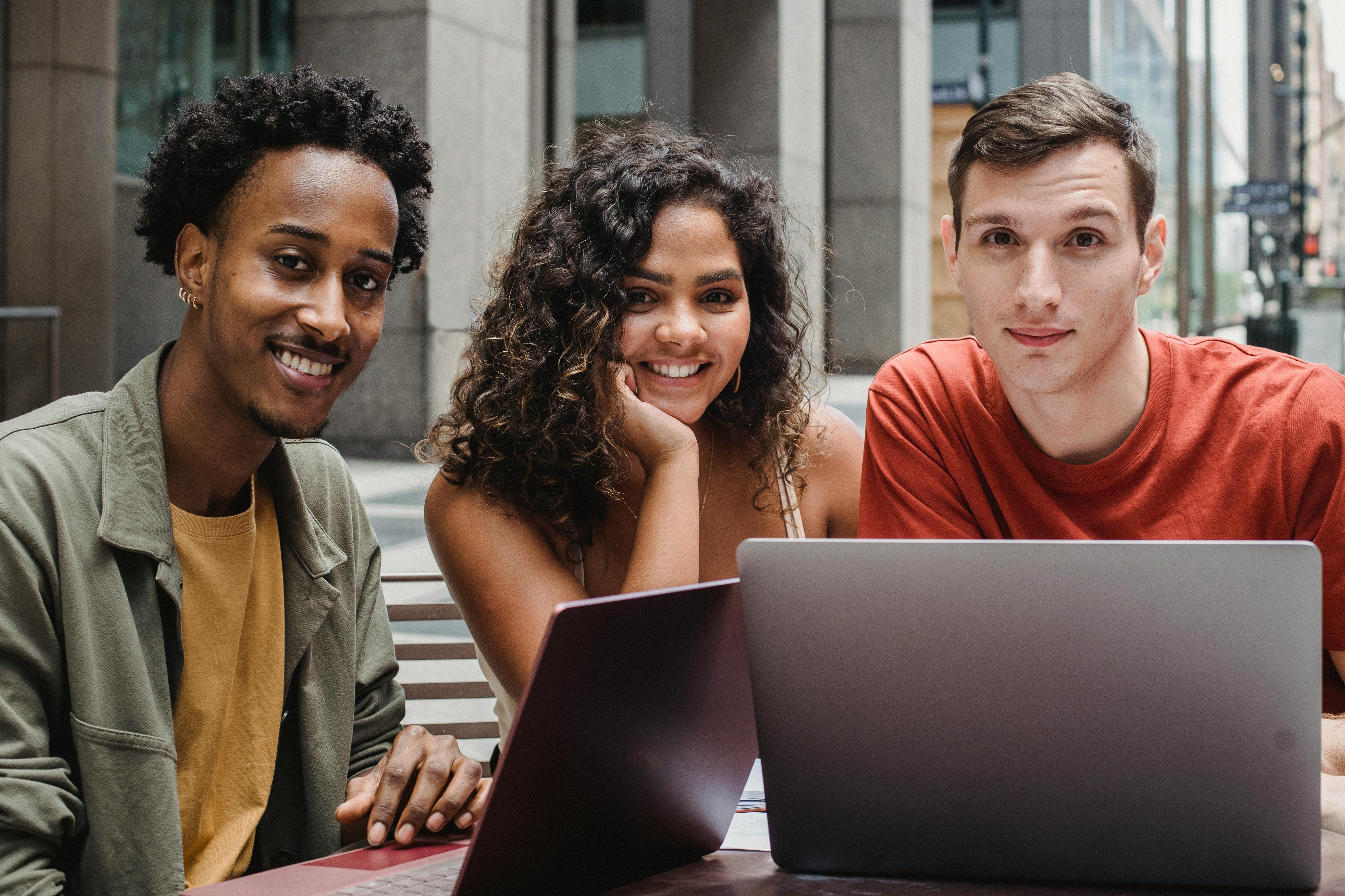 multiracial students working on laptop in street