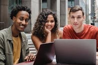 Multiracial students working on laptop in street