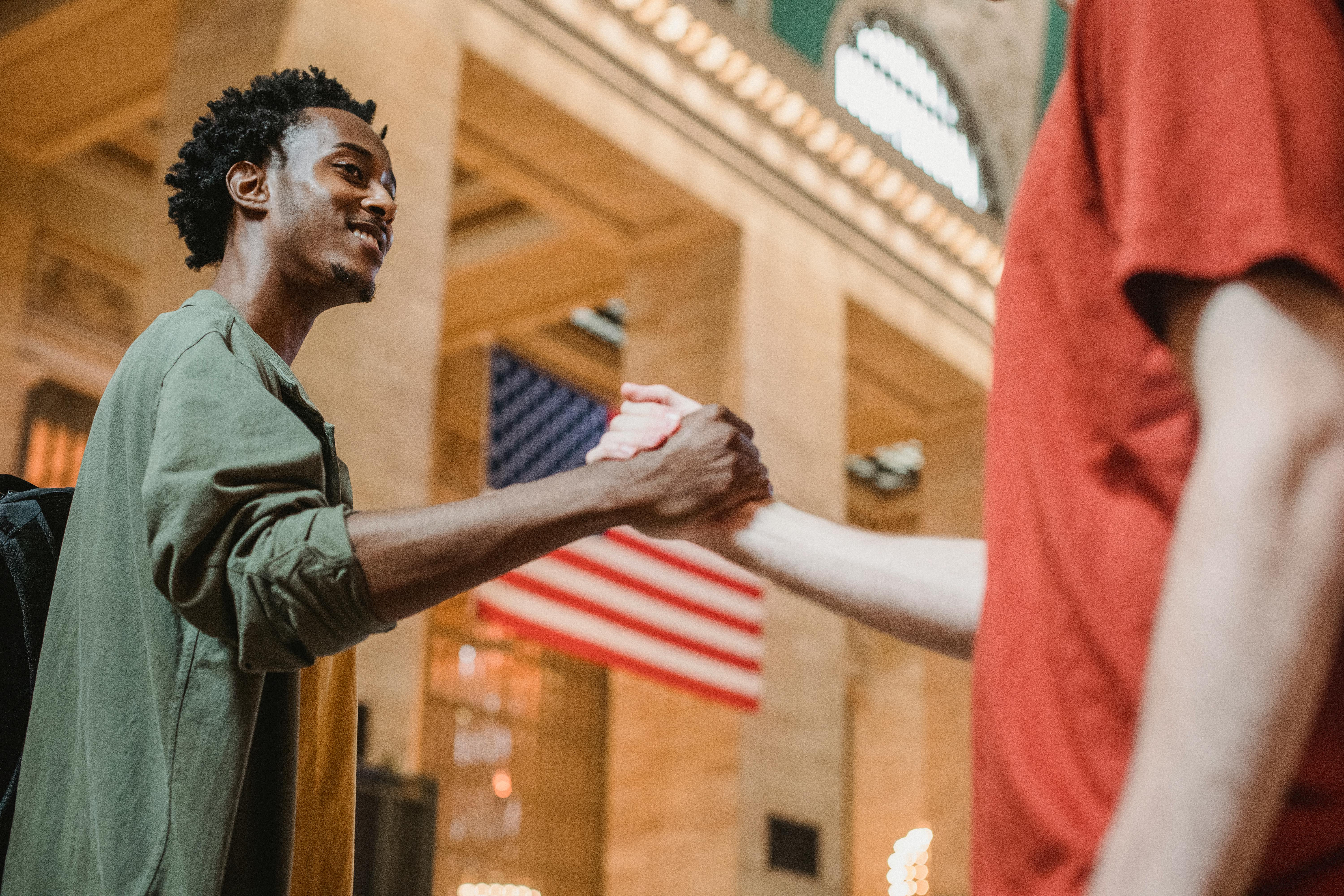 Smiling multiracial male friends shaking hands in building