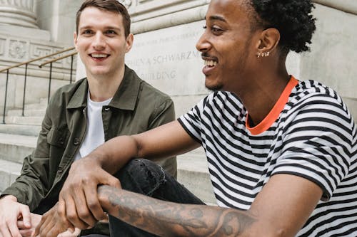 Happy multiracial male friends sitting on stairs in street