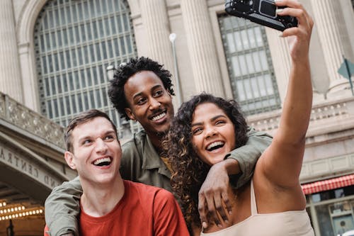 Free Happy multiethnic friends taking selfie in street Stock Photo