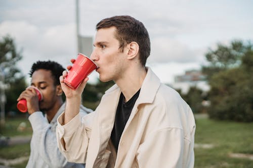 Man In Witte Jas Rode Plastic Beker Drinken