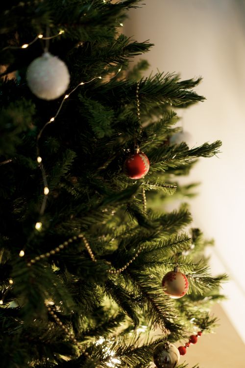 Free Close-up of a beautifully decorated Christmas tree with baubles and warm fairy lights indoors. Stock Photo