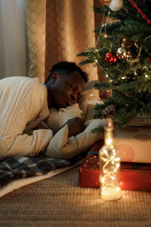 Free Man Sleeping Near a Christmas Tree Stock Photo