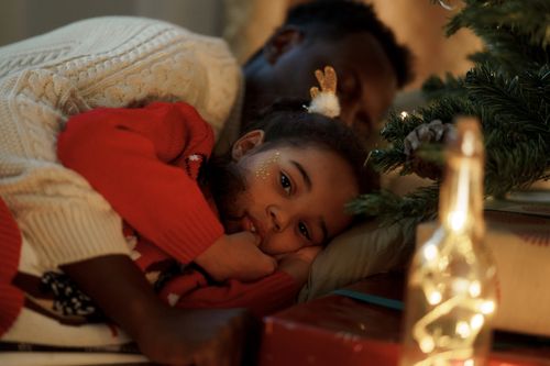 Free A father and daughter share a cozy moment by the Christmas tree, symbolizing love and warmth. Stock Photo