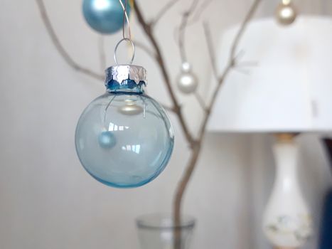 Elegant blue glass bauble hanging in a minimalist indoor setting, perfect for Christmas decoration ideas.