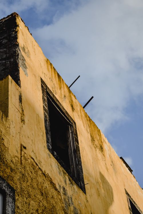 Free A low-angle view of an abandoned building with an open window in Funchal, Madeira. Stock Photo