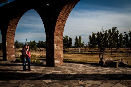 Free A couple embraces under a picturesque brick archway, embodying romance and love outdoors. Stock Photo