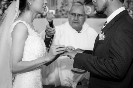 A monochrome image capturing a couple exchanging rings during their wedding ceremony.