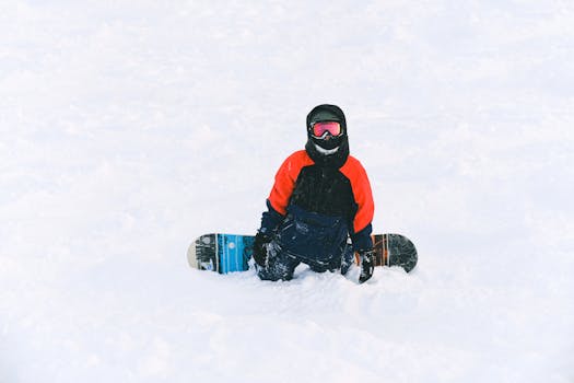 A snowboarder in winter gear relaxes on fresh snow, capturing the essence of winter sports adventure.
