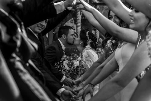 Grayscale Photo of Couple Kissing on Their Wedding Day