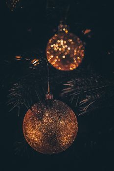 Close-up of shiny Christmas ornaments hanging on a tree branch.
