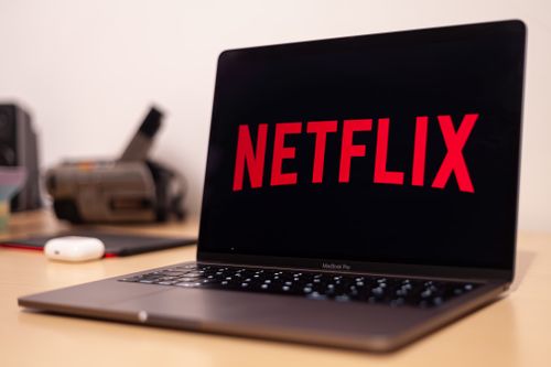 Free Close-up of a MacBook Pro showing Netflix on the screen in a modern workspace. Stock Photo