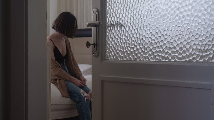 A Depressed Woman Sitting On The Bed