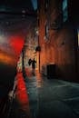 Back view of anonymous person with umbrella walking on street in rainy weather