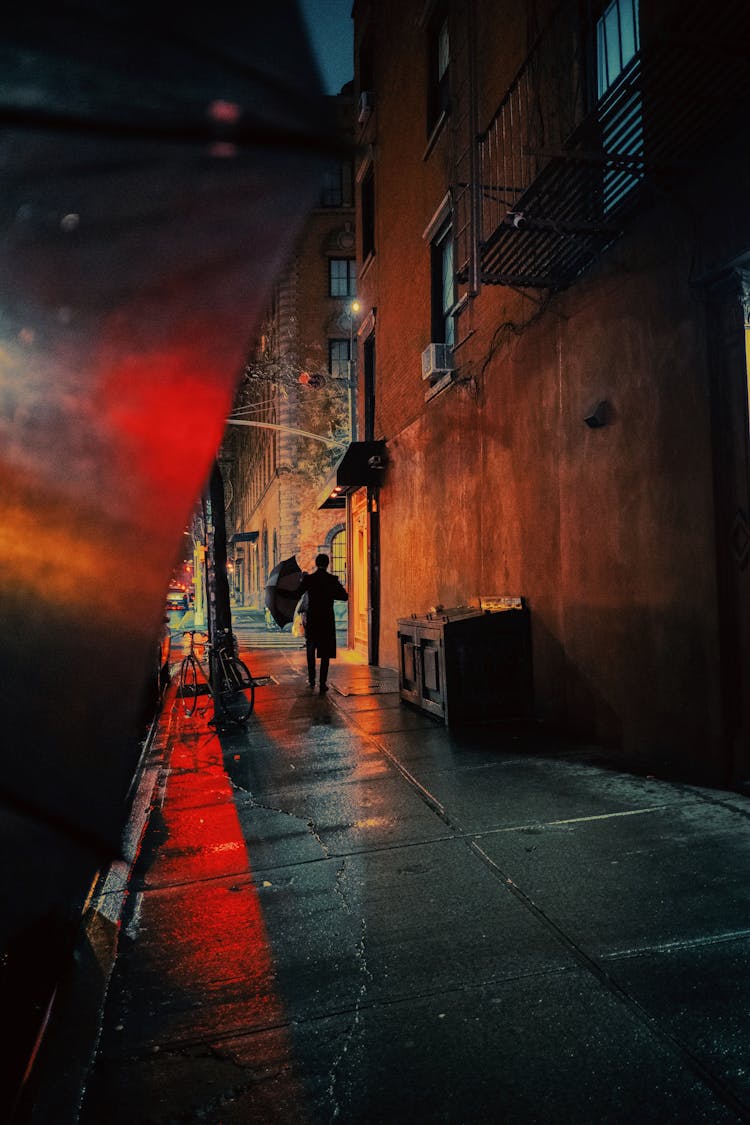 Silhouette Of Person With Umbrella On Street