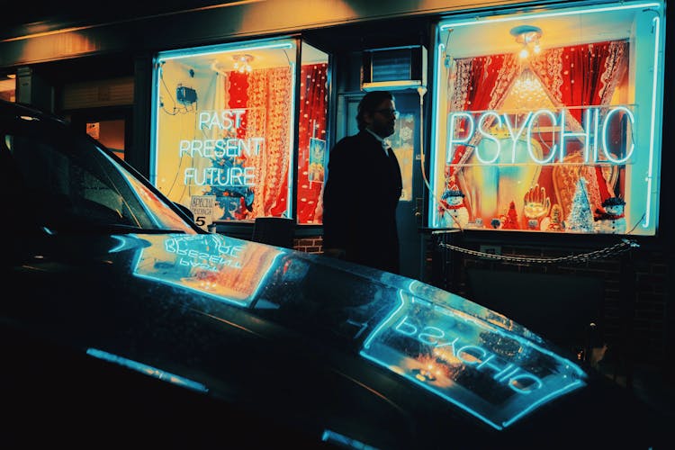 A Man In Black Coat Walking On The Street At Night