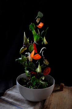 A vibrant display of fresh vegetables soaring above a bowl, showcasing dynamic food styling.