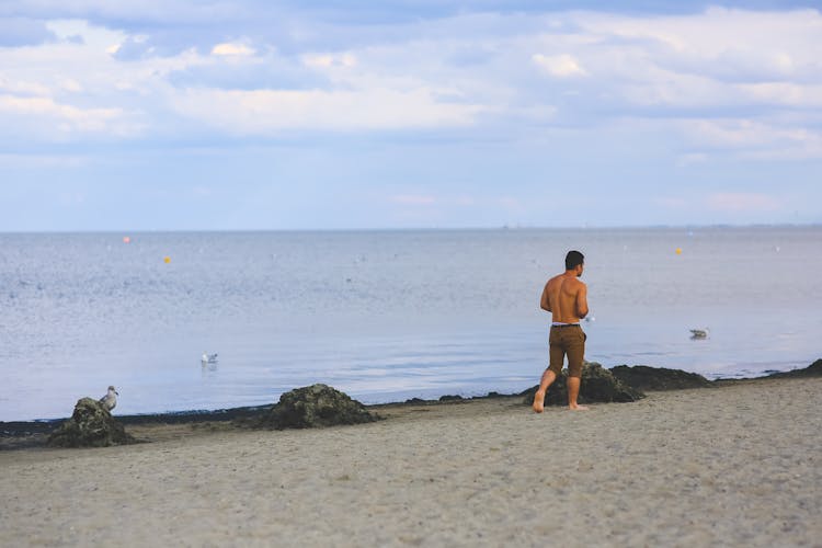 Young Man Walking On Sand Beach