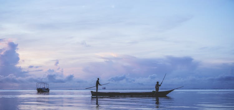 People Sailing In Canoe At Dawn