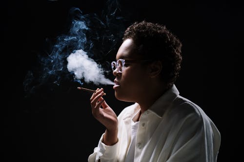 Close-Up Shot of a Woman in White Sleeves and with Eyeglasses Smoking