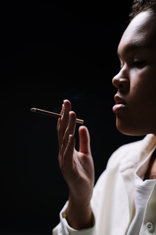 Close-Up Shot of a Woman in White Sleeves Holding a Cigarette