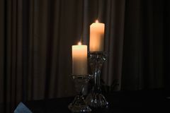 Two candles in glass holders casting warm light in a dark, elegant setting.