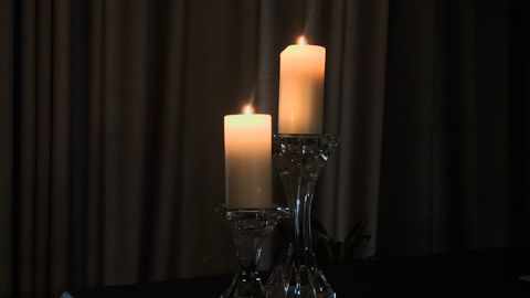 Two candles in glass holders casting warm light in a dark, elegant setting.