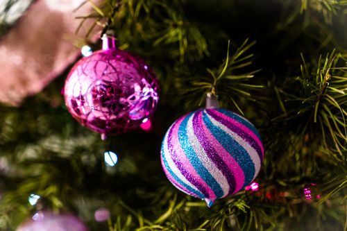 Free Close-up of colorful Christmas ornaments hanging on a tree, capturing the festive holiday spirit. Stock Photo