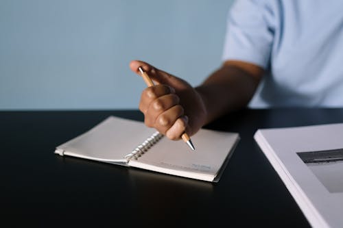 Close-Up Shot of a Person Writing on a Notebook