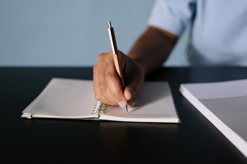 Free Close-Up Shot of a Person Writing on a Notebook Stock Photo