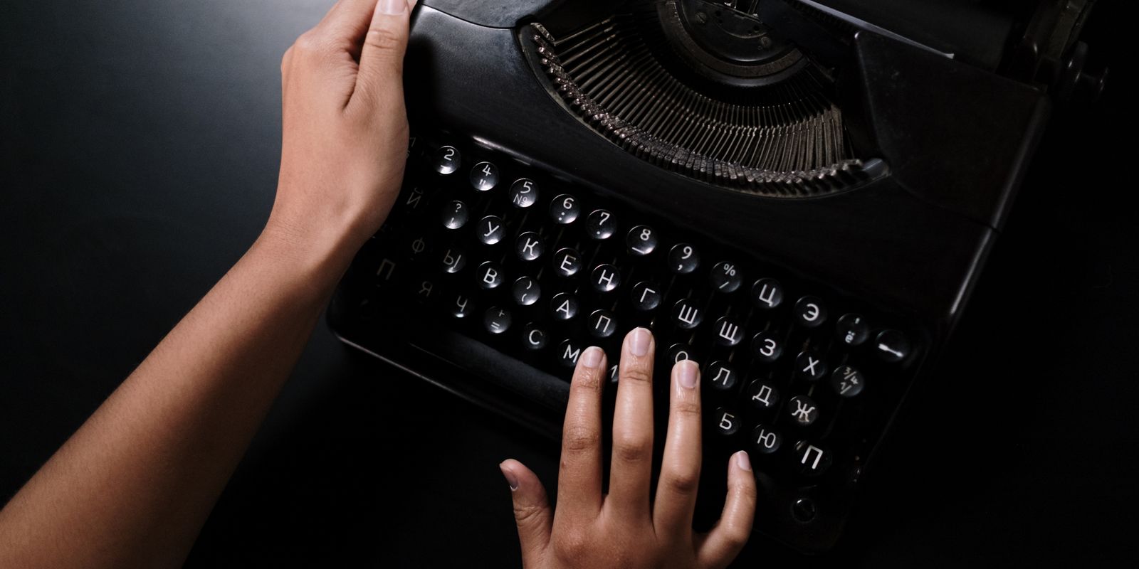 Hands typing on a vintage black typewriter