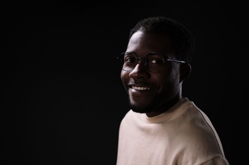 Free Close-up portrait of a smiling man wearing glasses against a dark background. Stock Photo