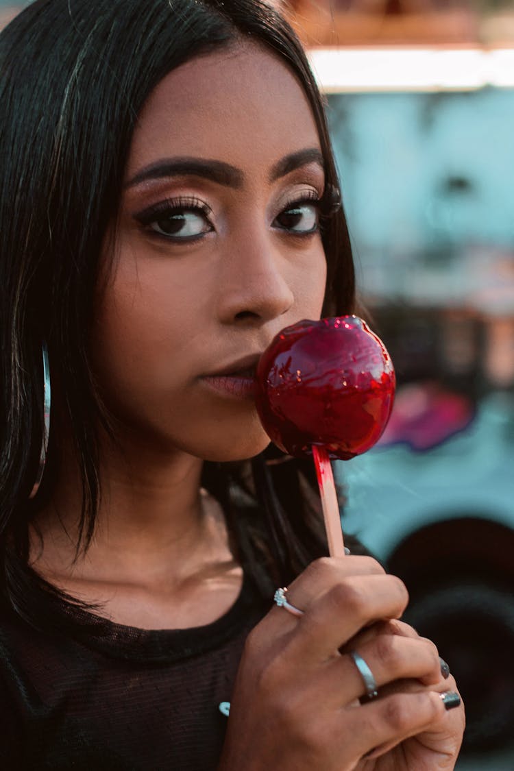 Crop Ethnic Lady With Candy Apple On Blurred Urban Background