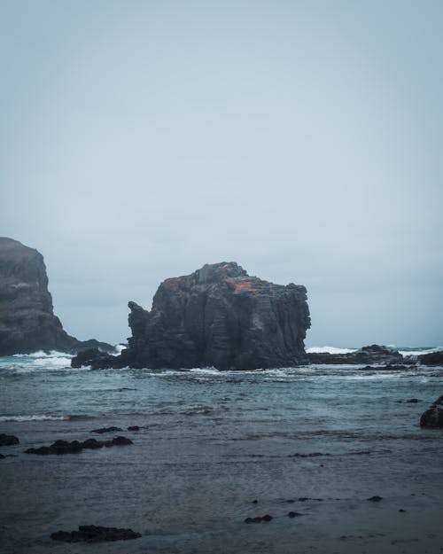 Brown Rock Formation on Sea During Gloomy Weather