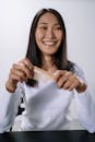 Smiling Woman in White Long Sleeve Shirt Holding Brown Wooden Stick