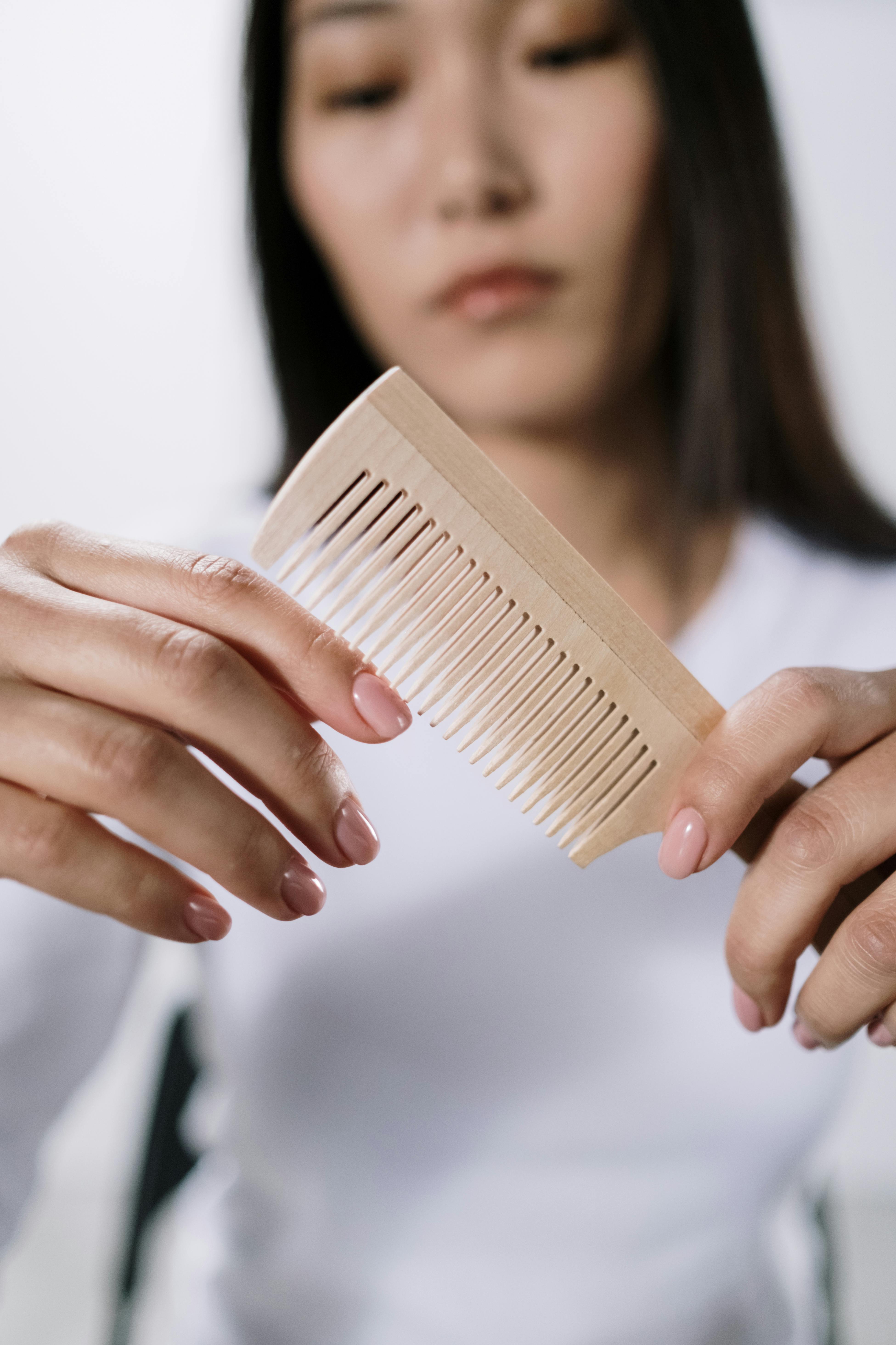A detailed shot of a woman holding a wooden comb, focusing on grooming.
