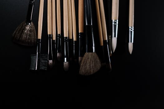 Close-up of various makeup brushes on a black background, ideal for beauty and fashion concepts.