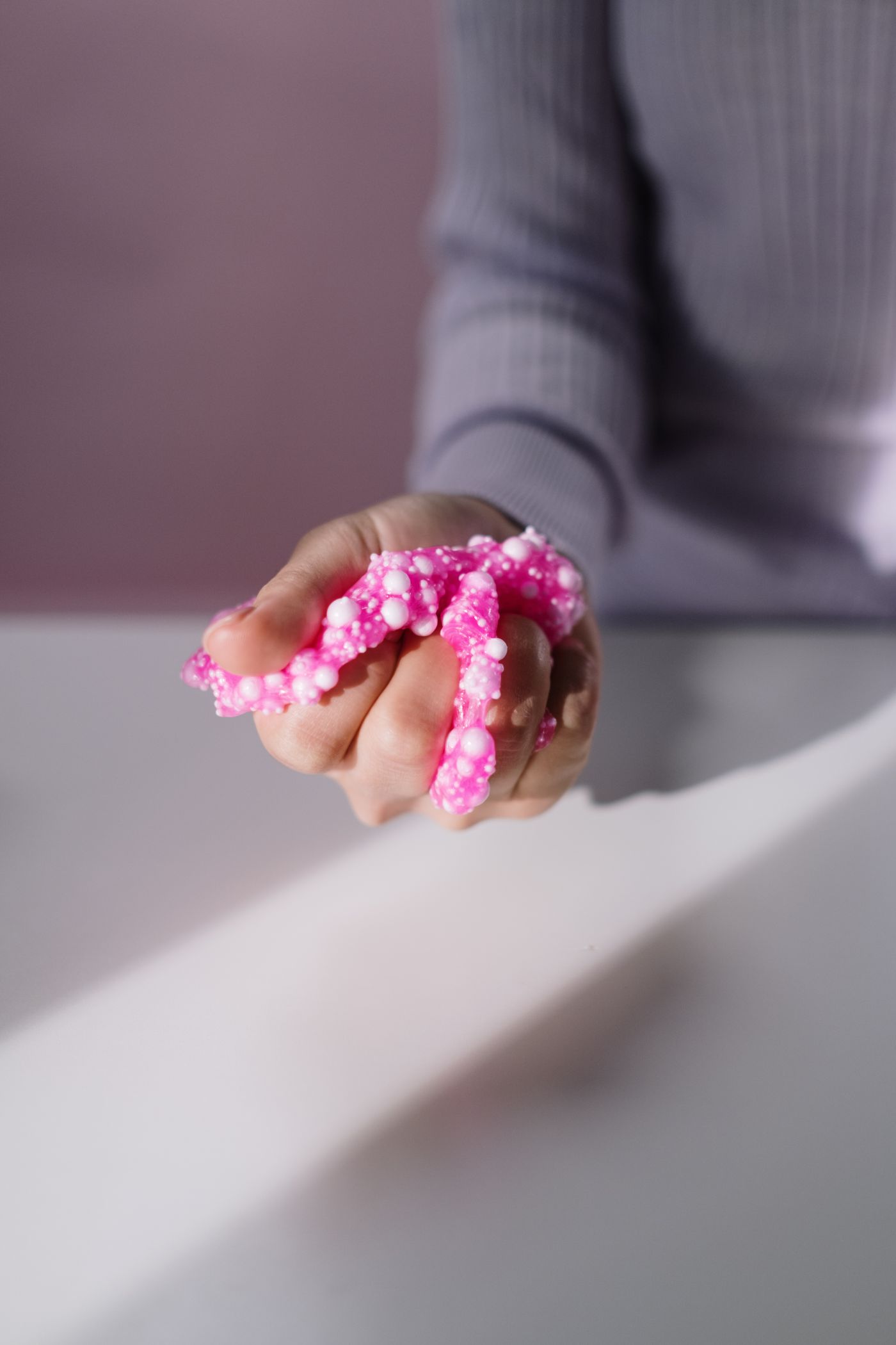 Hand holding bright pink foam slime
