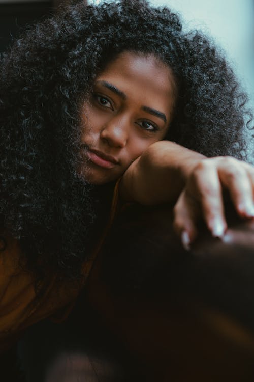 Young thoughtful black woman sitting near window