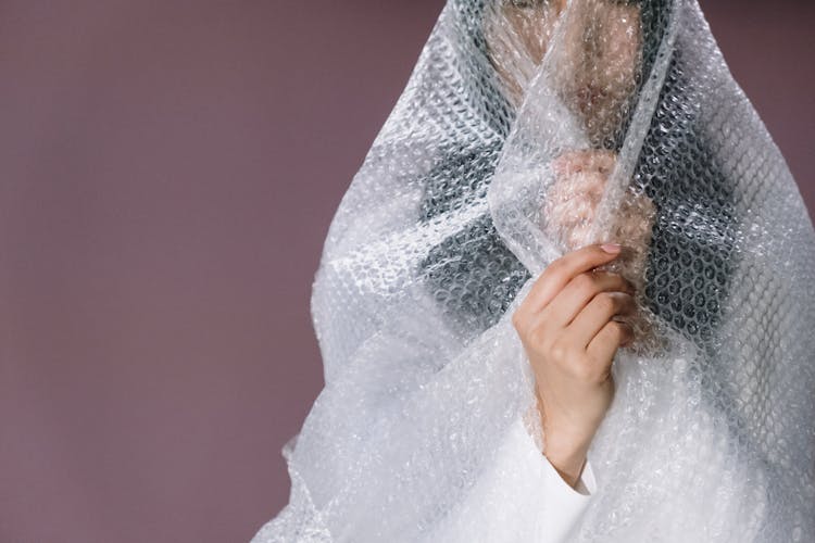 Woman In White Long Sleeve Shirt Holding White Plastic Bubble Wrap