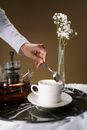 Person Pouring White Flower on White Ceramic Cup
