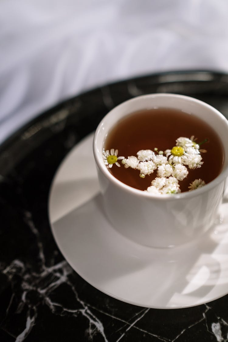 White Ceramic Cup With Tea And Flowers