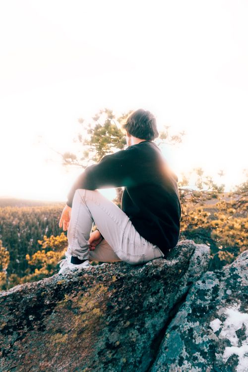 Free A man sits on a rock, meditating and enjoying the view of an autumn landscape. Stock Photo